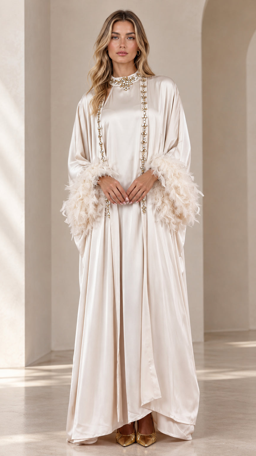 Front full view of woman wearing champagne satin maxi kaftan with embellished neckline and feather cuffs