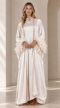 Front full view of woman wearing champagne satin maxi kaftan with embellished neckline and feather cuffs