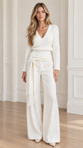Front full-length view of model wearing cream V-neck knit top and wide-leg pants set with fringe belt