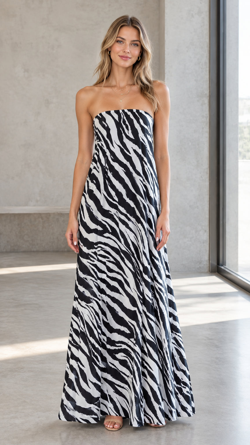 Front view of model wearing black and white strapless zebra print maxi dress