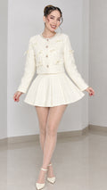 Front full view of model wearing cream tweed cropped jacket and pleated mini skirt set