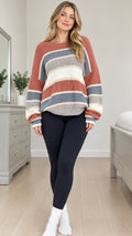 Full front view of model wearing rust colorblock striped crewneck knit sweater with black leggings