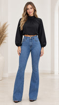 Full front view of model wearing black high neck crop top with blue high-waisted flare jeans