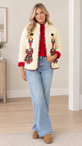 Full front view of model wearing cream quilted holiday jacket with nutcracker embroidery