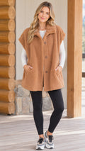 Front view of model wearing camel oversized teddy fleece tunic vest with black leggings