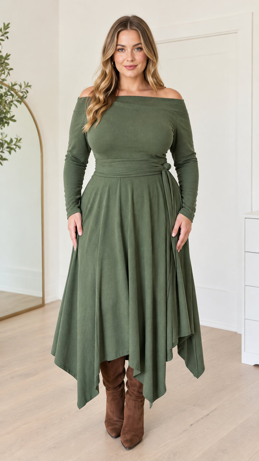 Front full-length view of woman wearing an olive green off-the-shoulder handkerchief midi dress with brown boots
