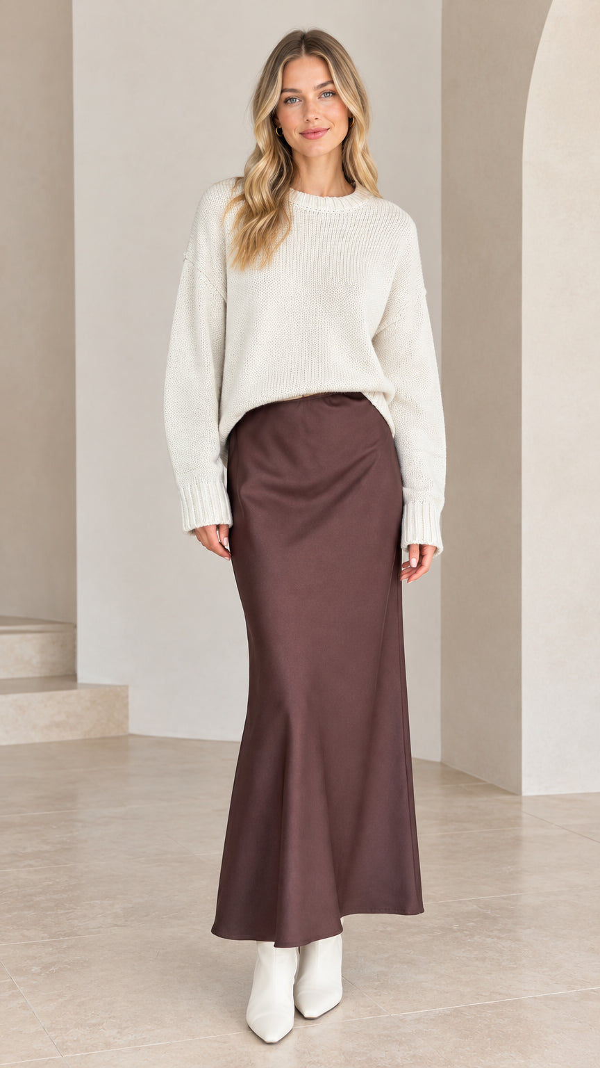 Model wearing white drop shoulder crew neck knit sweater tucked into brown satin skirt - front view