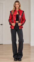Front full view of women's red faux leather moto jacket with black contrast stripes paired with dark jeans