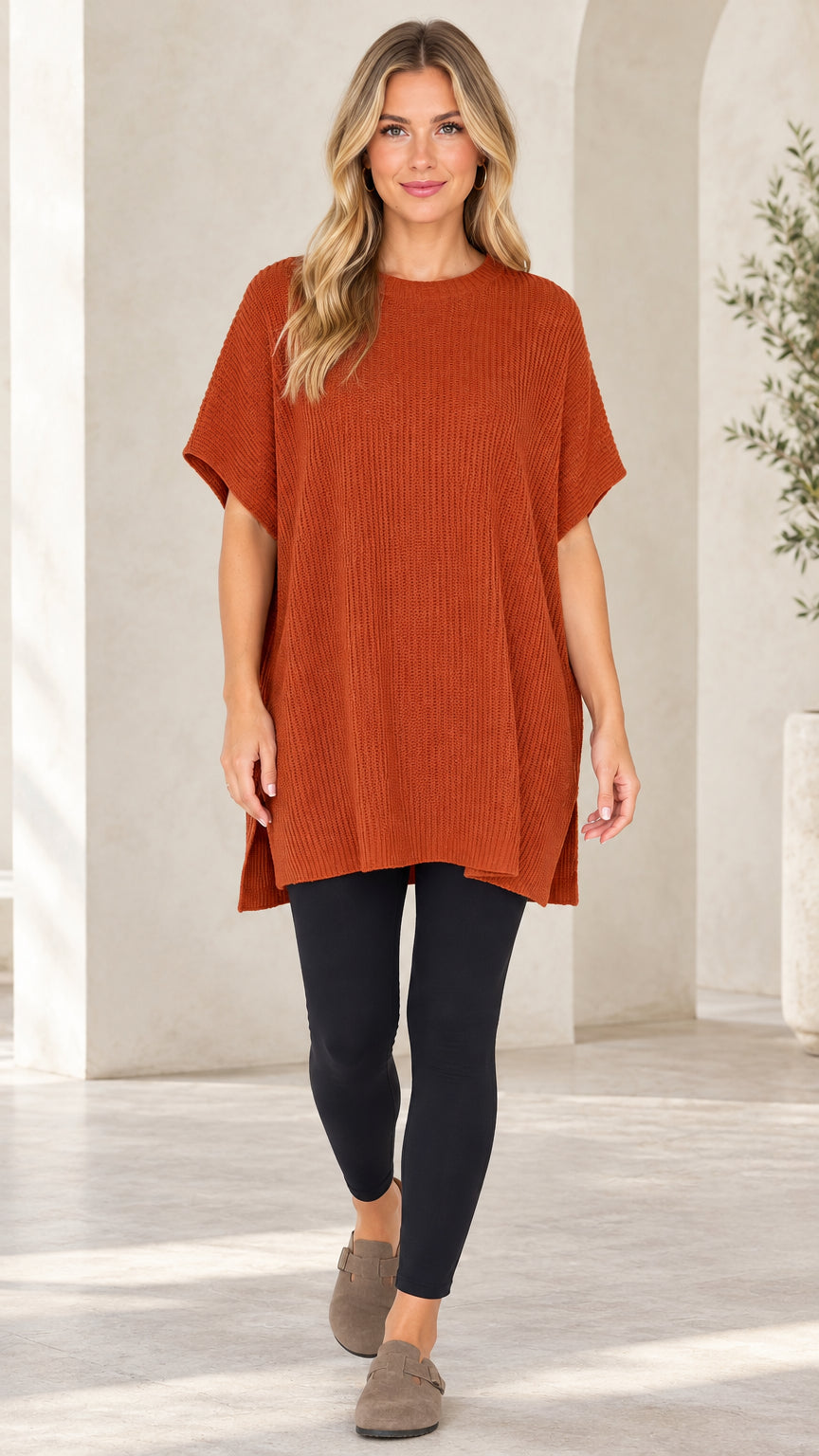 Front view of woman wearing rust orange ribbed knit short sleeve tunic sweater with black leggings