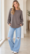 Front full view of woman wearing charcoal grey crewneck knit pullover sweatshirt with light wash jeans