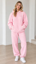 Front view of woman wearing pink oversized hoodie and matching sweatpants set