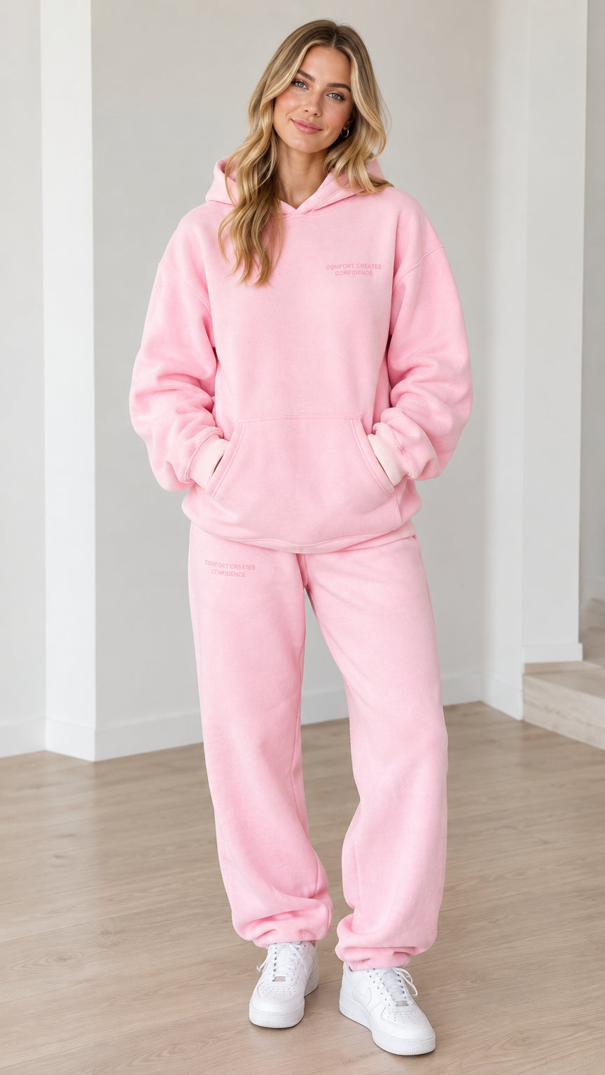 Front view of woman wearing pink oversized hoodie and matching sweatpants set
