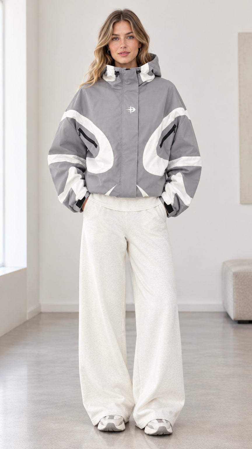 Front view of model wearing grey and white colorblock hooded jacket with wide-leg white pants