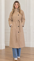 Front view of woman wearing camel high neck belted long overcoat with wide leg jeans