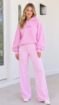 Front view of woman wearing pink hooded sweatshirt and pink gingham wide-leg pants set
