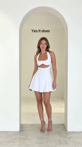 Front view of model wearing white halter neck cutout mini skater dress