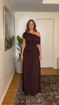 Front full-length view of woman wearing chocolate brown one-shoulder ruched maxi dress