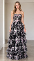 Front full-length view of model wearing black floral embroidered strapless tiered maxi gown