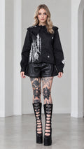 Full front view of model wearing black gothic castle print ruffled collar blouse with faux leather shorts and platform boots