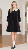 Front view of model wearing black velvet babydoll dress with white lace collar