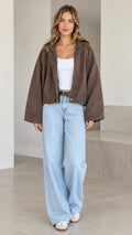 Front view of model wearing brown washed hooded cropped jacket with wide sleeves and jeans