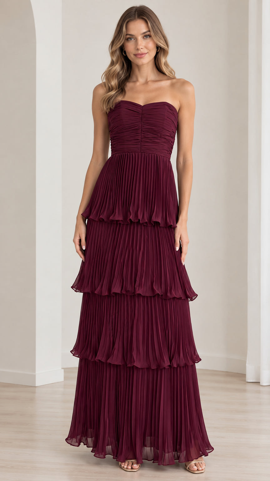 Front view of model wearing strapless burgundy tiered pleated maxi evening dress