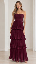 Front view of model wearing strapless burgundy tiered pleated maxi evening dress