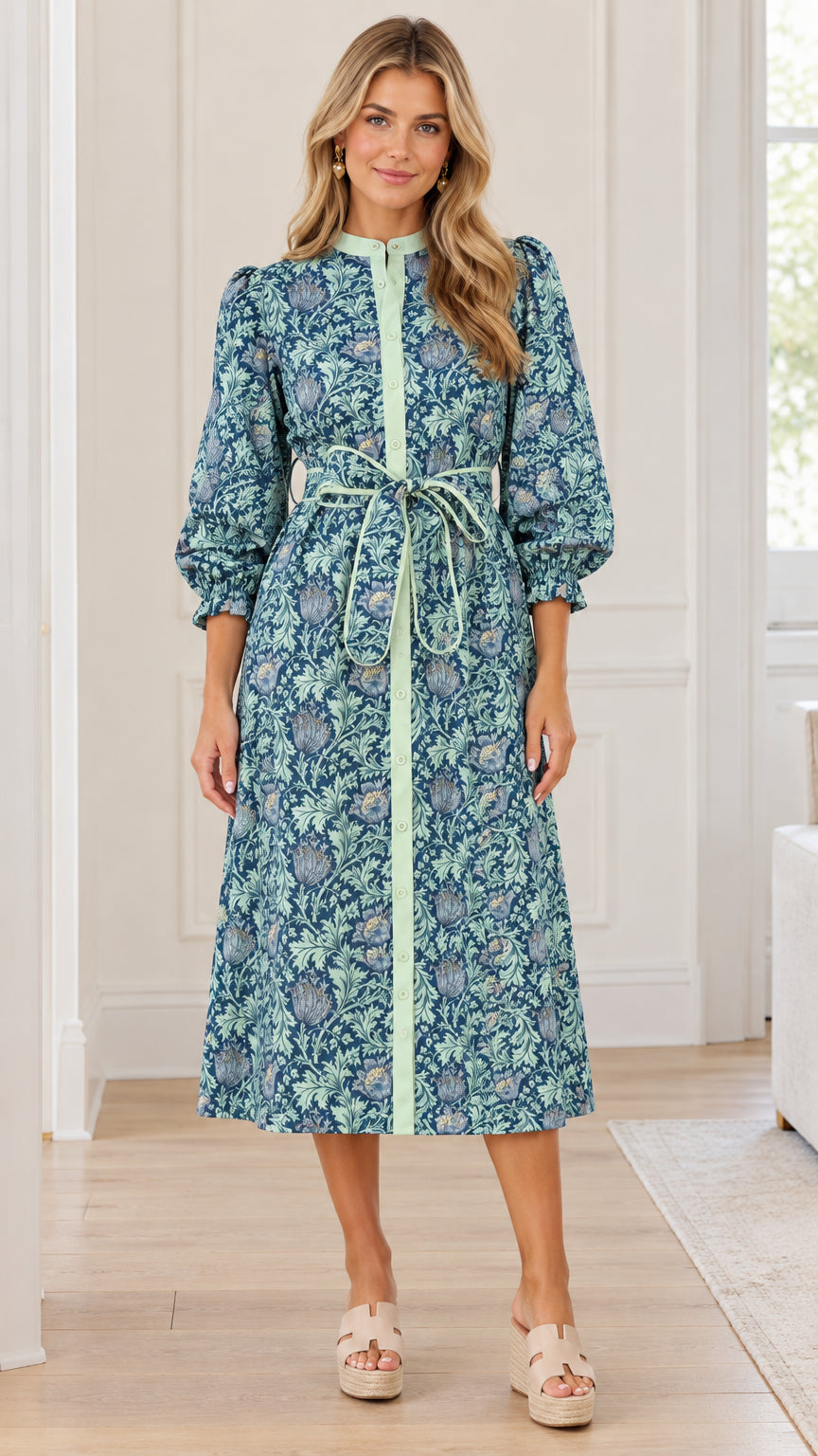 Front full view of woman wearing teal blue floral print midi shirt dress with tie waist belt