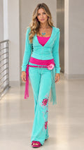 Front view of model wearing turquoise floral embroidered velour hoodie and flare pants tracksuit set
