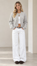 Front view of model wearing a heather grey cropped knit cardigan with metallic dome buttons and wide-leg white pants