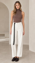 Front full view of woman wearing brown sleeveless mock turtleneck top paired with white wide-leg trousers