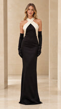 Front view of model wearing black two-tone cross halter evening gown with matching opera gloves