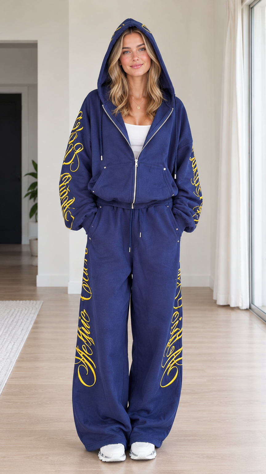 Front view of woman wearing royal blue script embroidered zip-up hoodie and wide-leg sweatpants set