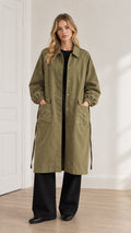 Full front view of a model wearing an olive green long duster coat with turn-down collar and wide-leg trousers