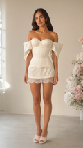 Full front view of model wearing ivory off-shoulder corset mini dress with lace hem