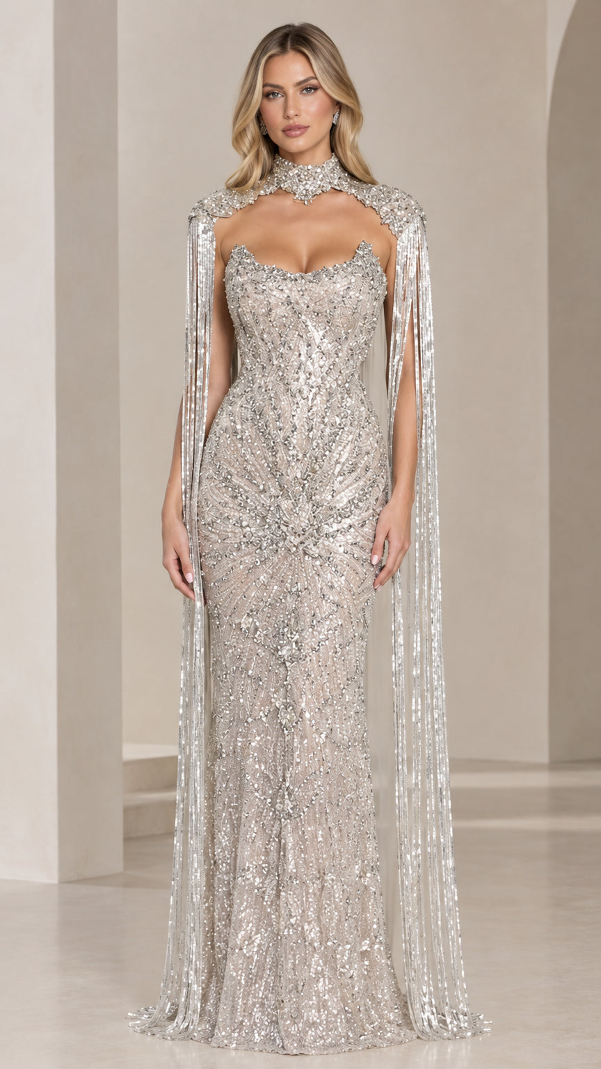 Front view of model wearing full-length silver beaded evening gown with high choker neckline and hanging beaded cape fringe