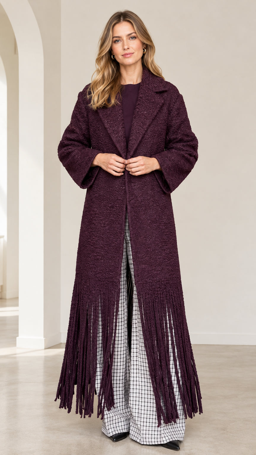 Full front view of model wearing burgundy textured bouclé maxi coat with dramatic fringe hem