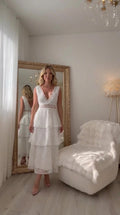 Front full-length view of woman wearing white sleeveless tiered lace midi dress with V-neck