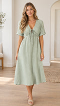 Front full-length view of woman wearing a sage green textured V-neck midi dress with front tie