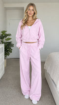 Model wearing light pink cropped zip hoodie and wide-leg sweatpants set front view