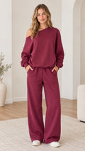Full front view of model wearing burgundy one-shoulder sweatshirt and wide-leg sweatpants set