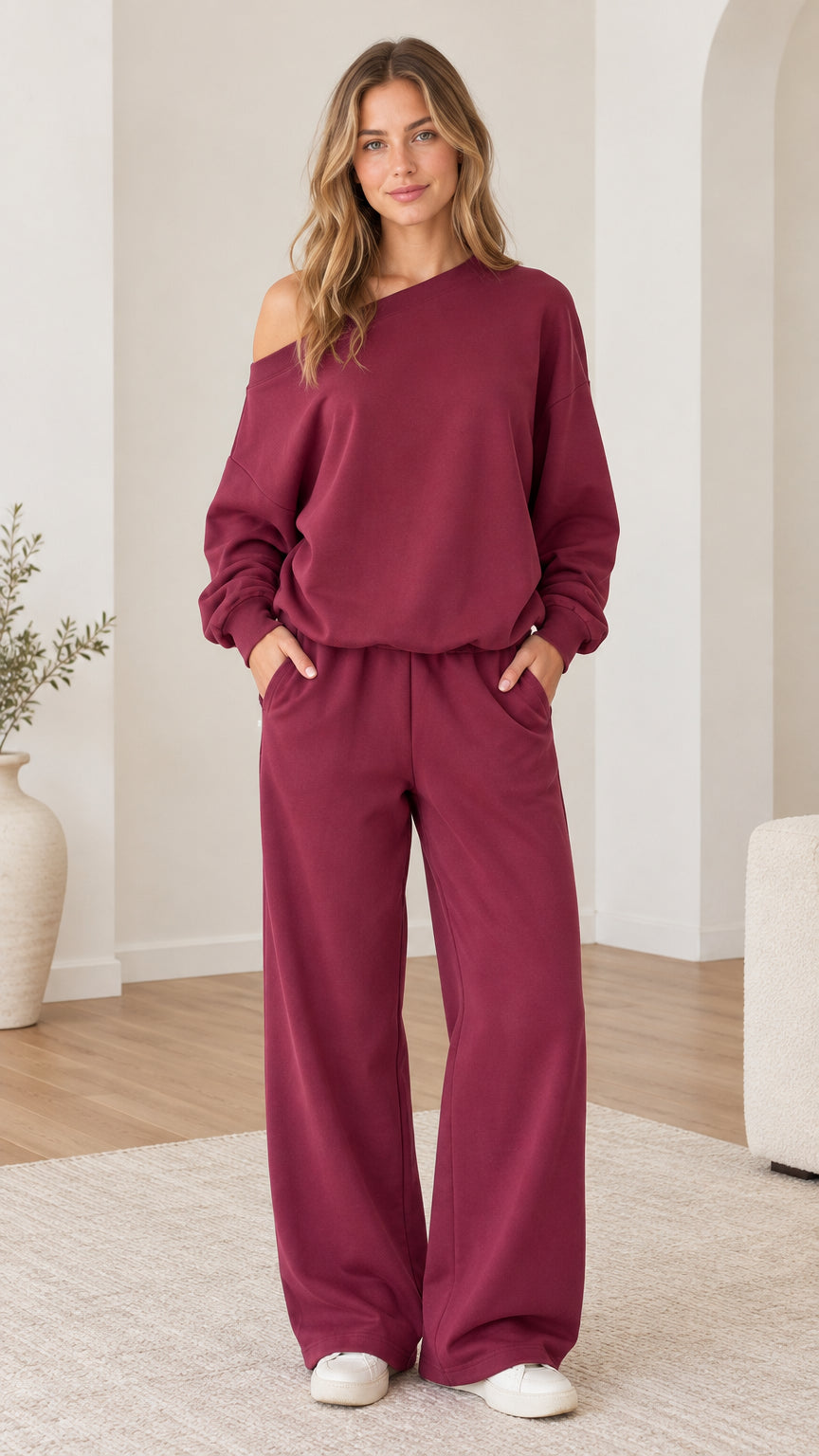 Full front view of model wearing burgundy one-shoulder sweatshirt and wide-leg sweatpants set