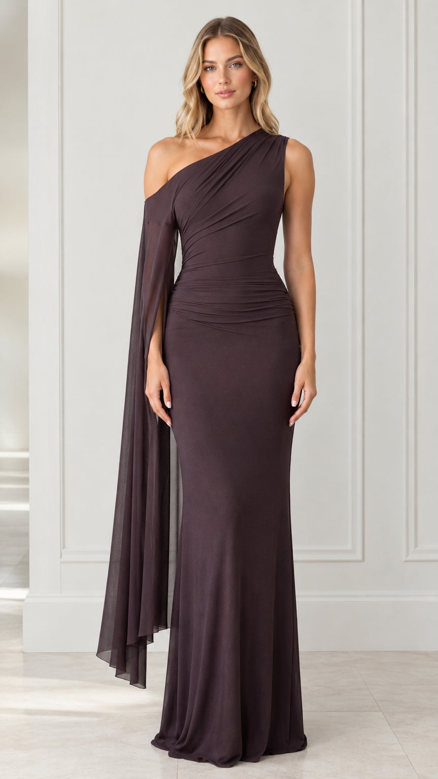 Front view of model wearing dark brown one-shoulder ruched maxi dress with draped cape sleeve