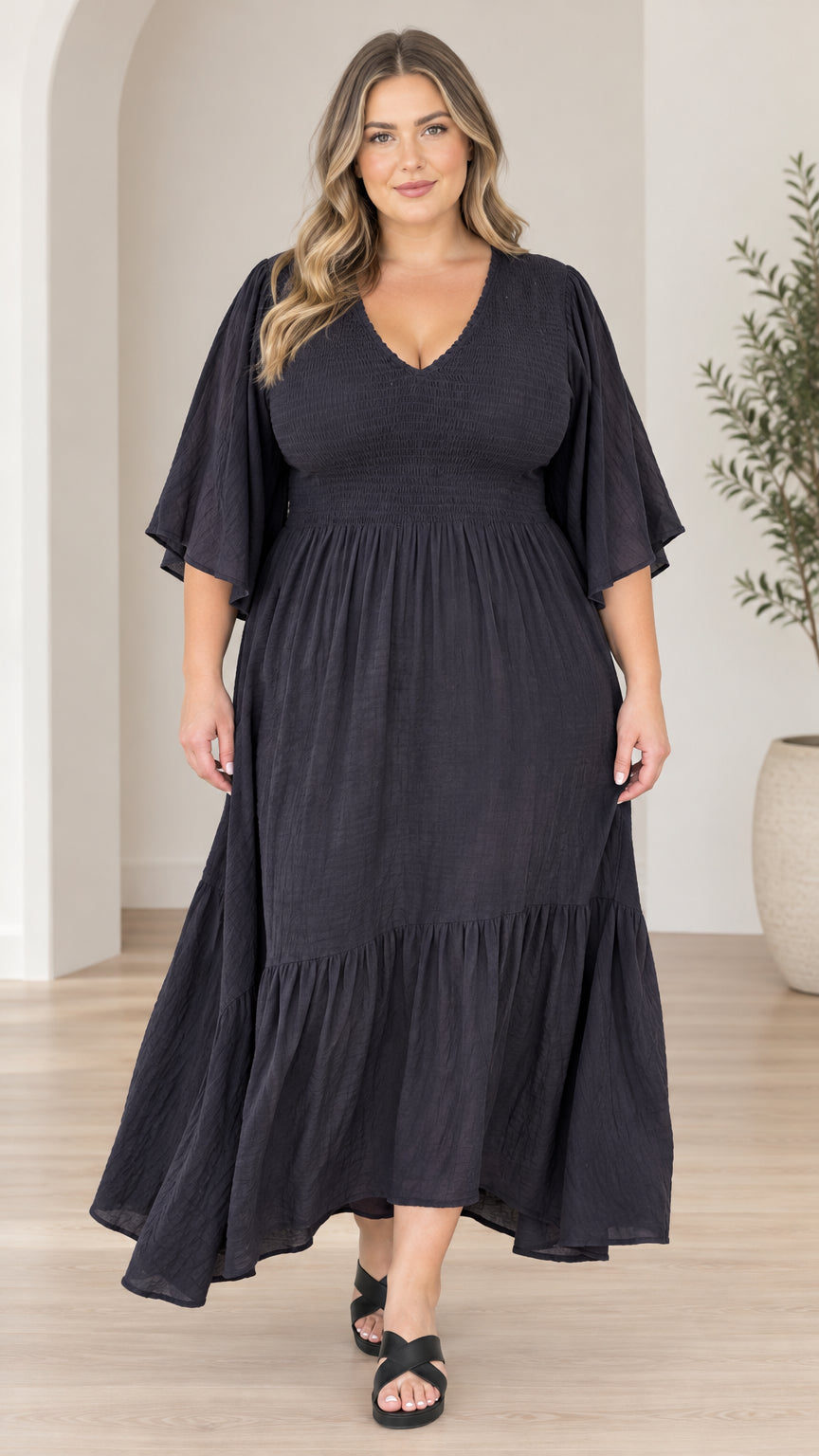 Front full-length view of model wearing black V-neck tiered maxi dress with flutter sleeves