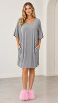 Front full view of a woman wearing the grey oversized short sleeve lounge dress with pockets