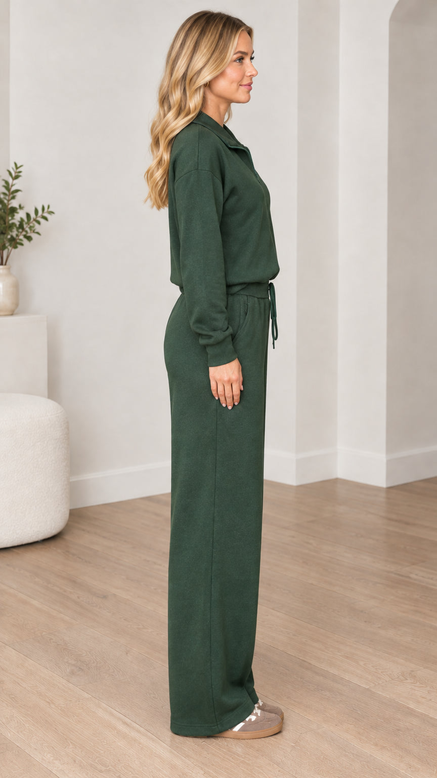 Side profile of model wearing forest green two-piece sweatshirt and matching trousers