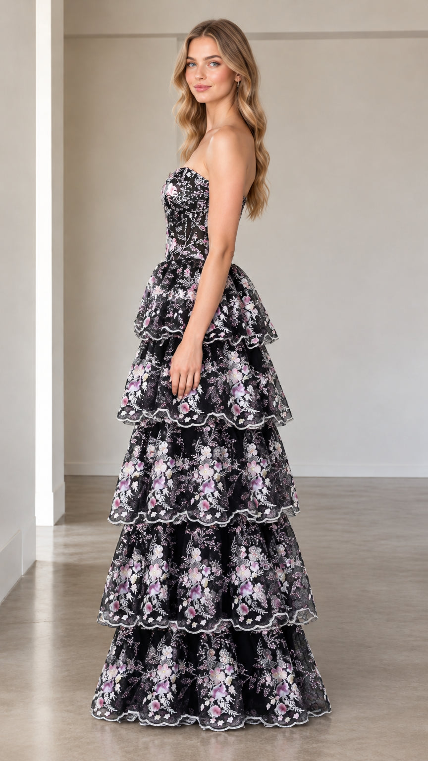 Side profile view of model wearing black floral embroidered tiered formal gown