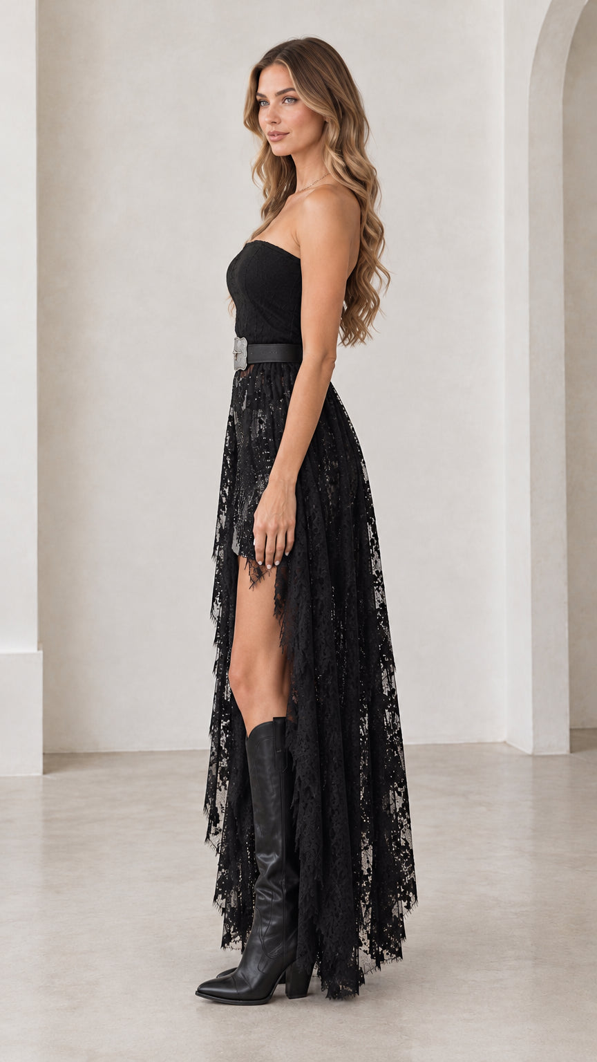 Side angle of model wearing black high-low lace dress with flowing sheer train