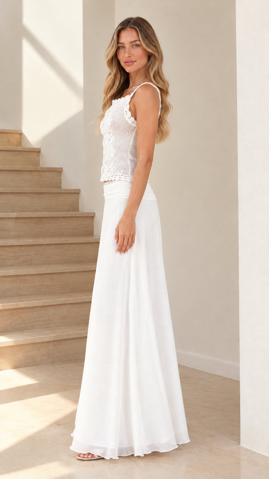 Side profile view of model in white lace camisole top and floor-length white maxi skirt