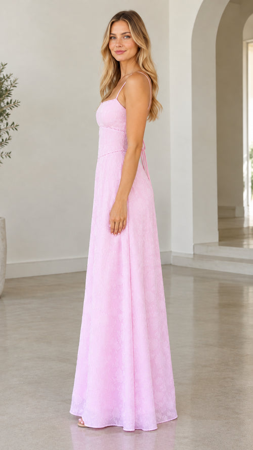 Side profile view of woman modeling pink floor-length spaghetti strap dress
